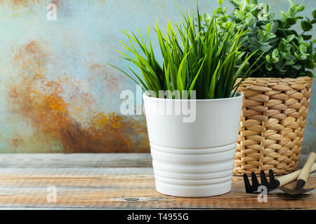 Plantes Vertes artificielles dans un pot à fleurs blanches se tenir sur la table en bois. Banque D'Images