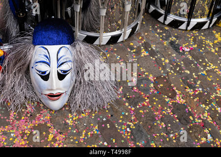 Augustinergasse, Bâle, Suisse - Mars 12th, 2019. Close-up d'un masque de carnaval et caisse claire sur une rue couverte de confettis Banque D'Images