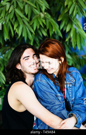 Portrait d'un jeune couple dans l'amour. Heureusement smiling red-haired woman est assis sur les genoux d'un beau, joyeux, insouciant laughing brunette l'homme. Banque D'Images