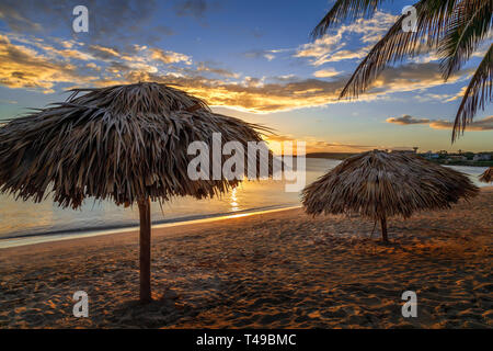 Rancho Luna Plage des caraïbes avec des palmiers et des parasols de paille sur la plage, Coucher de soleil vue, Cienfuegos, Cuba Banque D'Images