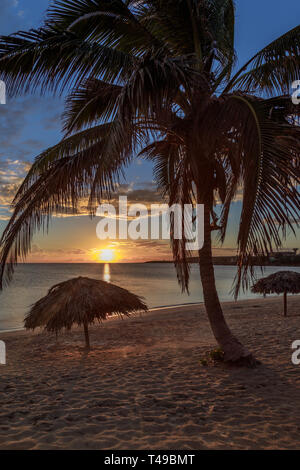 Rancho Luna Plage des caraïbes avec des palmiers et des parasols de paille sur la plage, Coucher de soleil vue, Cienfuegos, Cuba Banque D'Images