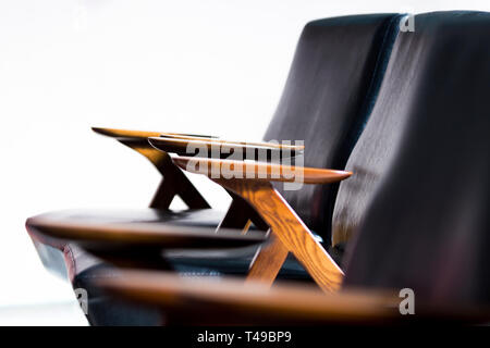 Portrait d'un couple de fauteuils en cuir et en bois retro de niveau du ventre dans un blanc, image, et sélective l'accent sur deux bras de toucher chaque oth Banque D'Images