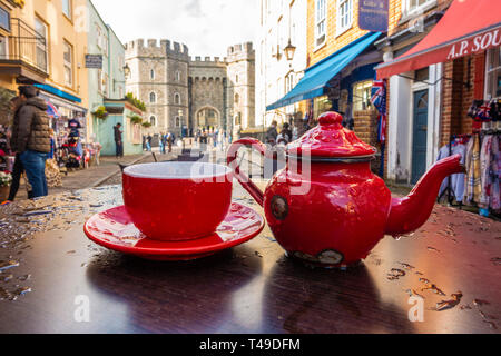 Un verre d'un rouge vif, et une théière soucoupe forment une pièce maîtresse attirant l'œil sur la terrasse d'un café dans la rue de l'église de table, Windsor, Royaume-Uni Banque D'Images