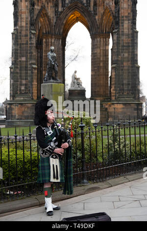 L'homme vêtu d'un kilt écossais et jouer de la cornemuse en face du Scott Monument à l'auteur Sir Walter Scott, Édimbourg, Écosse Banque D'Images