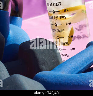 Une sélection de Kettlebells et haltères avec une bouteille d'eau douce avec des morceaux de lime et de citron. Banque D'Images
