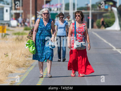 Vue de face d'une paire de femmes d'âge moyen de marcher ensemble vers l'appareil photo le long de la promenade du front de mer de Littlehampton, West Sussex, Angleterre, Royaume-Uni. Banque D'Images