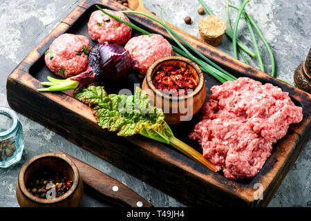 Matière première fraîche hachée de bœuf sur une planche à découper et ingrédients Banque D'Images