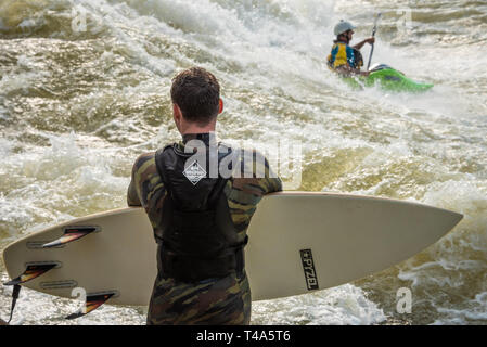 River surfer attend son tour comme un kayakiste d'eau vive les manèges freestyle de la bonne vague sur la rivière Chattahoochee à Columbus, en Géorgie. (USA) Banque D'Images