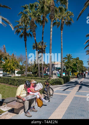 Vélo mature couple prendre une pause pour lire leurs nouvelles sur chemin côtier à San Pedro de Alcantara, Malaga Espagne Banque D'Images