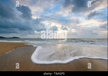 Ciel d'orage et de douces vagues spume au lever du soleil, Palm Cove Cairns, Plages du Nord, Extrême Nord du Queensland, Australie, Queensland, FNQ Banque D'Images