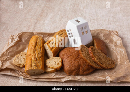 Ciabatta pain différent sans levure. Du pain frais en papier avec la maison blanche sur la toile de fond. L'alimentation saine et de la famille concept. Banque D'Images