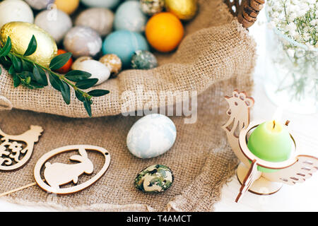 Joyeuses Pâques. Les oeufs de Pâques bougie, élégant, pain de Pâques cake, jambon, betteraves, saucisses, beurre, branches vertes dans panier en osier blanc sur fond de bois Banque D'Images