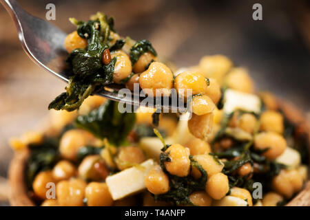 Libre d'une salade de pois chiches, avec les épinards, les pignons, l'oignon et fromage, servi dans un bol en buis rustique, placée sur une table rustique Banque D'Images