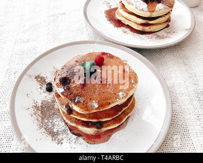 De délicieuses crêpes au sirop et de baies sur la plaque sur la table rustique élégant. Délicieux petit-déjeuner maison. Pile de crêpes avec confiture close up, idéal loisir Banque D'Images