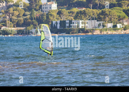 Planche à voile, planche à voile en face de l'Olivette Harbour au cap d'Antibes, Juan les Pins, Provence, Cote d'Azur, France Banque D'Images