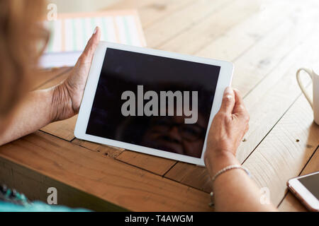Plus d'épaule d'un senior woman's hands holding a tablet computer, selective focus Banque D'Images