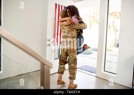 Le retour du soldat noir millénaire de lever son épouse au large de ses pieds à la porte de leur maison Banque D'Images