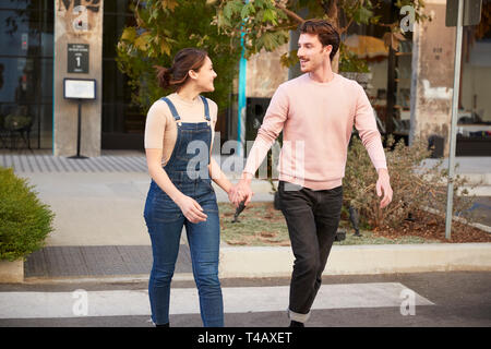 Couple hipster millénaire traversent la route dans la ville tenant les mains, Close up Banque D'Images
