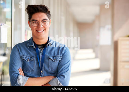 Portrait Of Smiling Male School Teacher Standing In Corridor of College Building Banque D'Images