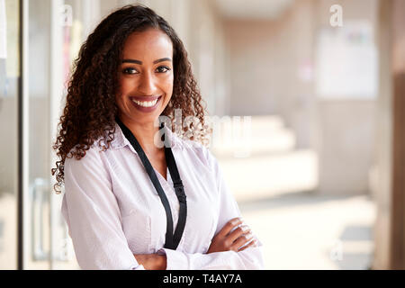 Portrait Of Smiling Female School Teacher Standing In Corridor of College Building Banque D'Images