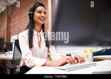 L'agent des services à la clientèle féminine travaillant au Bureau en Centre d'appel Banque D'Images