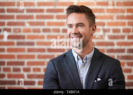 Young businessman standing Against brick wall in Modern Office Banque D'Images