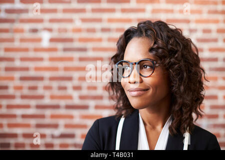 Smiling Businesswoman Wearing Glasses Standing Against brick wall in Modern Office Banque D'Images