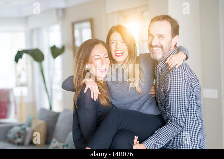 Belle famille ensemble. La mère, le père et sa fille en souriant et serrant avec amour à la maison. Banque D'Images