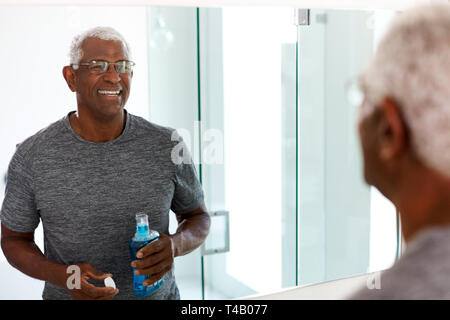 Senior de rince-bouche à la réflexion en miroir de salle à Wearing pajamas Banque D'Images