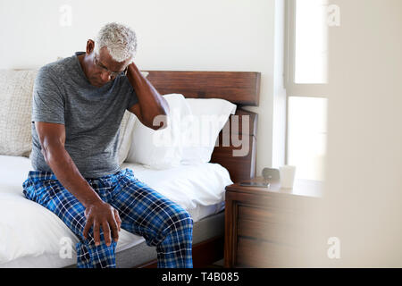 Hauts homme souffrant de douleur au cou assis sur le côté du lit à la maison Banque D'Images