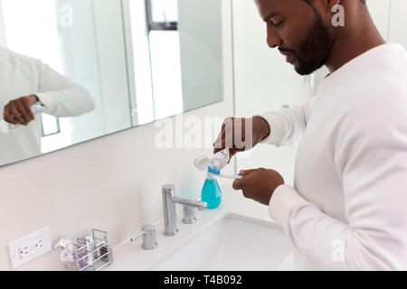 Close Up of Man squeezing dentifrice sur une brosse à dents dans la salle de bains Banque D'Images