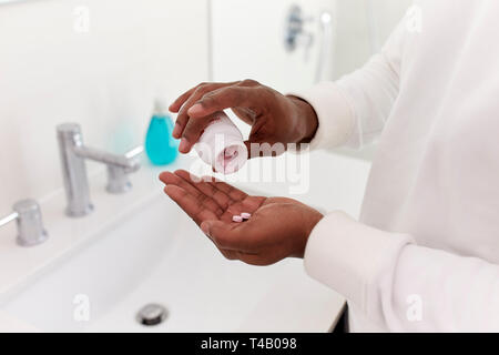 Close Up de l'homme dans la salle de bains prenant des comprimés de supplément de vitamine Banque D'Images