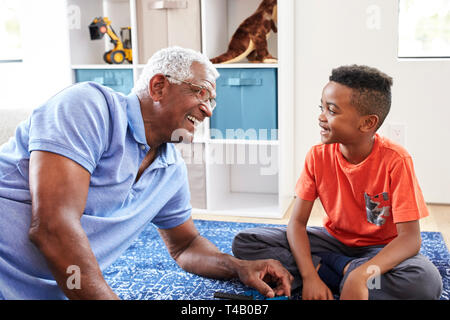 Grand-père avec son petit-fils couché sur un tapis à la maison modèle de construction ensemble Banque D'Images