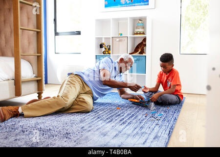 Grand-père avec son petit-fils couché sur un tapis à la maison modèle de construction ensemble Banque D'Images