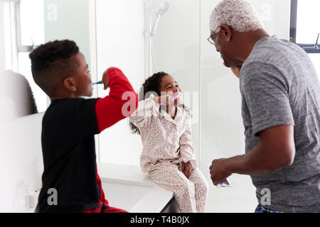 Grand-père dans la salle de bains Wearing Pajamas se brosser les dents avec des petits-enfants Banque D'Images