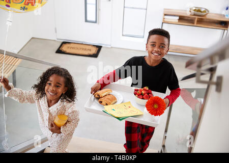 Les parents des enfants portant un petit déjeuner au lit sur le plateau pour célébrer la Fête des Mères, Fête des Pères Banque D'Images