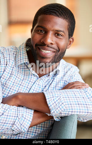Portrait Of Smiling Man Relaxing On Sofa At Home Banque D'Images