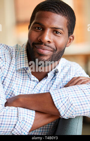 Portrait Of Smiling Man Relaxing On Sofa At Home Banque D'Images
