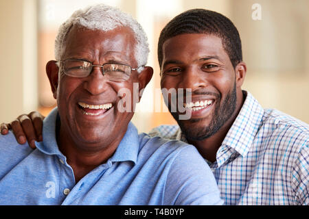 Portrait Of Smiling Senior Père câlins par fils adulte à la maison Banque D'Images