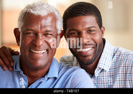 Portrait Of Smiling Senior Père câlins par fils adulte à la maison Banque D'Images