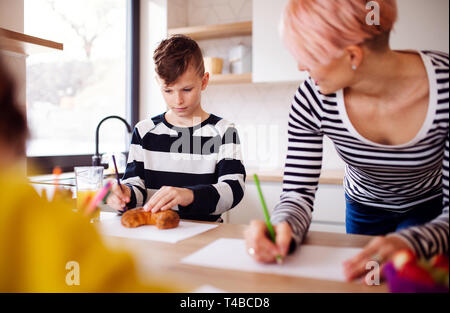 Une jeune femme avec deux enfants dessin dans une cuisine. Banque D'Images