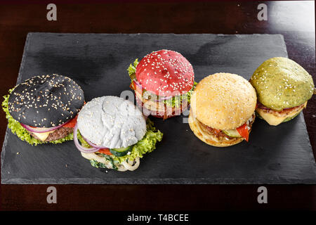 Les galettes de pains de différentes couleurs sur un tableau noir. clairement visible la texture des brioches et plombages Banque D'Images