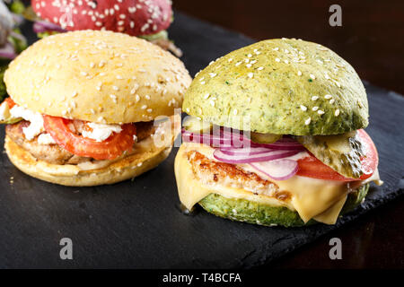 Les galettes de pains de différentes couleurs sur un tableau noir. clairement visible la texture des brioches et plombages Banque D'Images