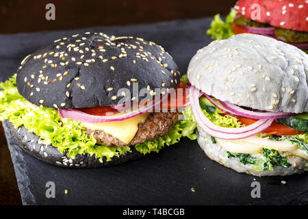 Les galettes de pains de différentes couleurs sur un tableau noir. clairement visible la texture des brioches et plombages Banque D'Images