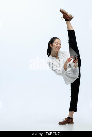 La flexibilité future. Une femme asiatique avec un smartphone en costume de style bureau debout sur fond blanc. Nouvelle technologie de la reconnaissance du visage sur grille polygonale. Concept de cyber sécurité, affaires, travail. Banque D'Images