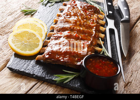 Côtes de porc barbecue traditionnel servi avec sauce épicée et de citron sur une table de bois horizontal. Banque D'Images