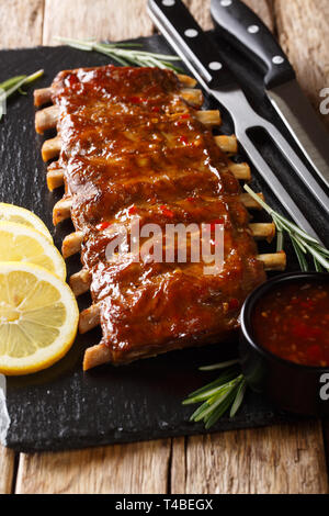 Délicieux avec des côtes de porc grillées épicées sauce chili et gros plan sur un citron conseil d'ardoise verticale. Banque D'Images
