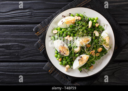 Printemps vert salade faite de pois verts, micro, les noix et les oeufs Gros plan sur une assiette sur la table. haut horizontale Vue de dessus Banque D'Images