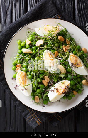 Délicieux salade saine de pois verts, pousses, les noix et les oeufs cuits sur une assiette sur la table. Haut Vertical Vue de dessus Banque D'Images