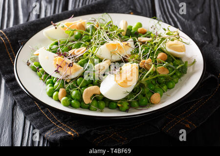 Salade saine avec les pois frais, œufs, noix et microgreen close-up sur une plaque sur la table horizontale. Banque D'Images